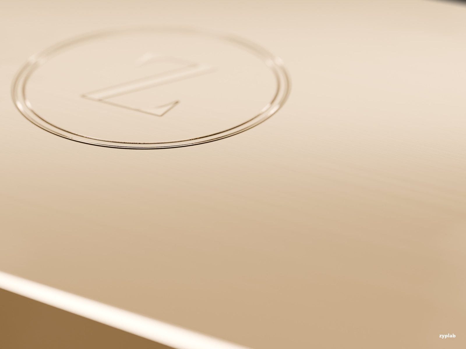 Macro of the debossed monogram and chamfered edge on brushed gold metal